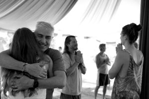 People sharing an emotional moment under a white tent canopy.