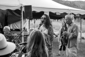 Musicians perform together on outdoor stage with instruments and microphones.
