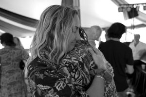 A side profile view of attendees participating in a group event under a tent.
