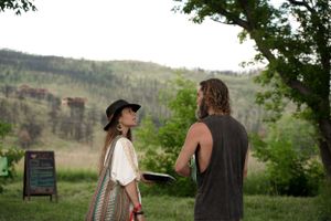 Two people having a conversation outdoors with mountains visible in the background.