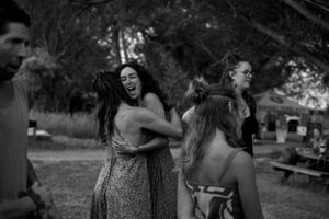 Friends dancing and laughing together at an outdoor summer celebration.