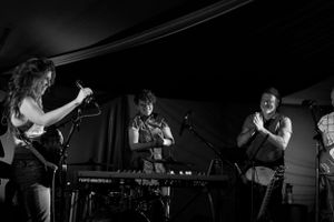 Musicians perform together on a dark stage with instruments.