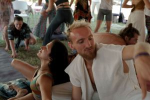 Group movement workshop participants stretching under white tent canopy.