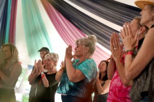 Group of people clapping and participating in what appears to be a celebratory gathering under colorful drapes.