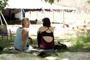 Two people sitting together on the ground enjoying a peaceful moment outdoors near hanging laundry.