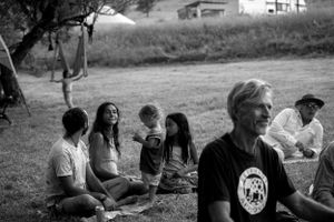A group sits together on grass during an outdoor gathering in black and white.