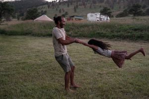 Someone playfully spins another person around in a field during sunset.