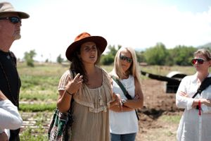 A summer gathering of people wearing sun hats in a rustic outdoor setting.