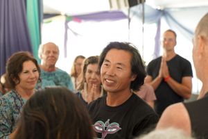A joyful gathering of people participating in a group activity under a decorated tent.