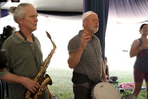 Musicians performing with saxophone and other instruments under an outdoor tent.