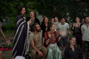 A diverse group of people enjoying entertainment outdoors with animated expressions.