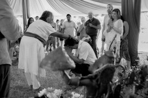 A ceremonial gathering takes place under a draped tent in black and white photography.
