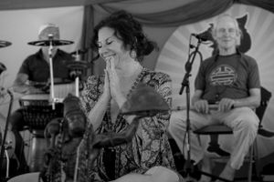 Musicians performing on stage under decorated festival tent lighting.