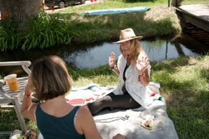 Two people having a picnic near a pond on a sunny afternoon.