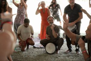 Festive crowd dancing and playing drums at an outdoor celebration.