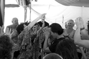 People raise their hands in celebration during a group activity under draped fabric decor.