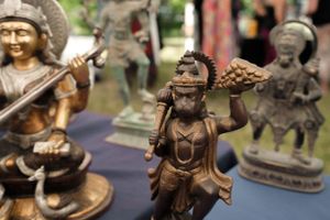 Bronze figurines of musicians and deities arranged on display at market.