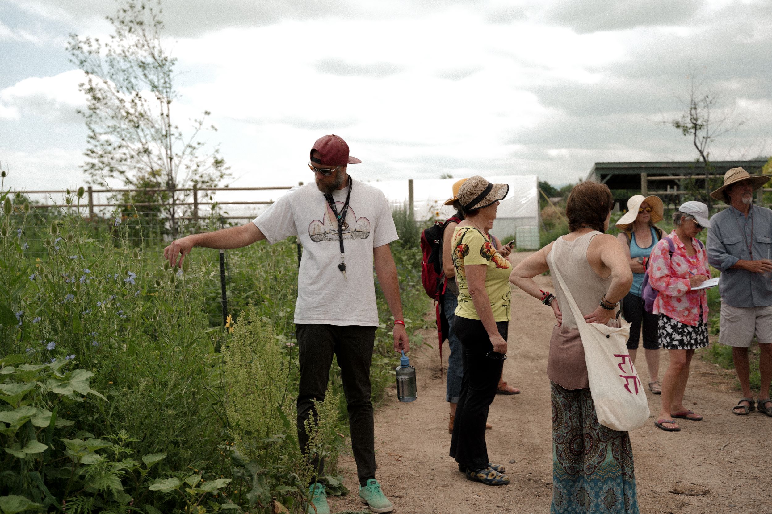 A group of people gathered outdoors in a garden or farm setting on a cloudy day.