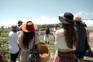 Group of visitors touring an outdoor farm wearing sun protection hats.