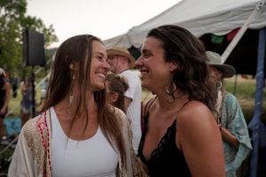Two people share an intimate moment of laughter at a casual outdoor gathering.
