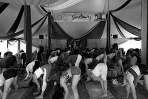 Black and white photo of yoga participants during a group class under draped fabric ceiling.