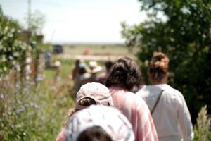A line of event attendees walking through a scenic outdoor trail.