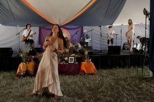 Performance on outdoor stage with musicians and dancers in front of draped backdrop.