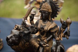 Detailed bronze statue of Hindu deity riding a lion displayed at market stall.