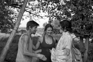 A casual outdoor conversation between friends in a natural setting captured in black and white.