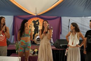 Performers on stage under colorful draping at what appears to be a festival or celebration.