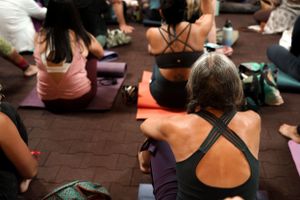 Back view of yoga participants sitting on mats during an indoor class.