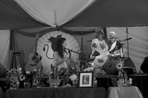 Black and white photo of decorative altar setup with candles and artwork in tent setting.