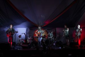 A band performs on stage under dramatic red lighting at night.