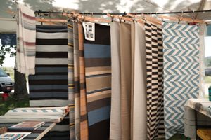 Various patterned textiles and fabrics hanging on display at an outdoor market or vendor booth.