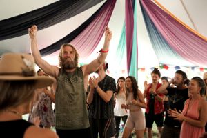 An energetic performance scene under a tent with colorful draped fabric decorations.