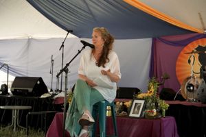 A performer sings on a decorated outdoor stage under a large white and orange tent.