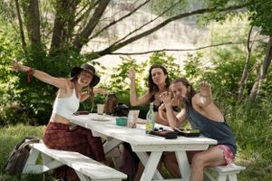Group enjoying a casual picnic lunch at a white outdoor table in a garden setting.
