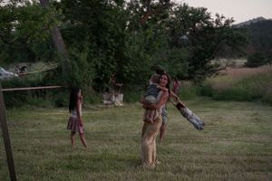 People playing and spinning in a grassy field at dusk with mountains in the background.