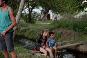 People rest by a small stream or creek on a summer day.