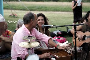 Musicians performing at an outdoor event with instruments and equipment set up on the grass.