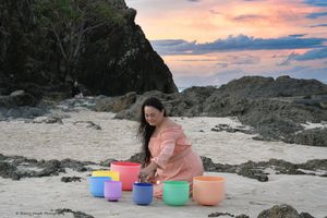 Portrait of a young lady on the beach with her sound bowls
