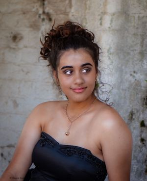 Portrait of a young lady sitting by a wall