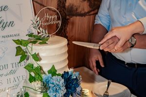Wedding reception table decorated with blue hydrangeas, greenery and elegant signage at an indoor venue.