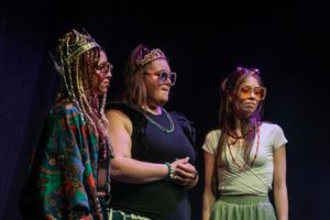 Three performers share a moment together on stage during a show.