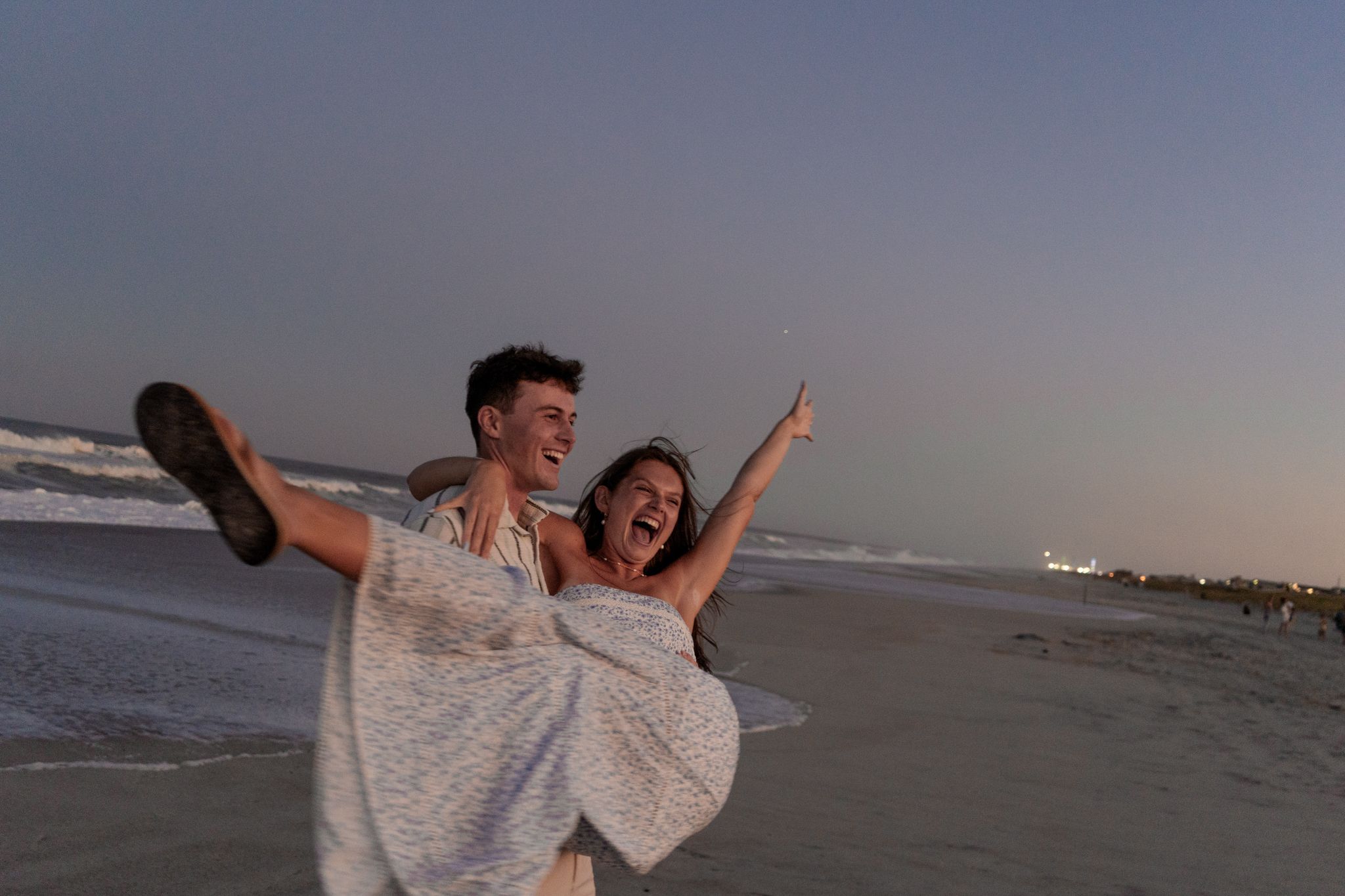 Joyful moment captured at beach with sunset and ocean waves in background.