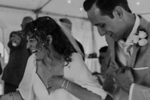 A black and white candid moment of a joyful couple dancing at their wedding reception.