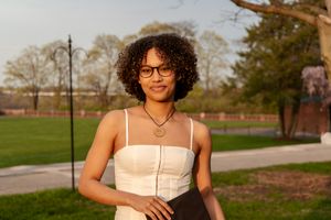 A person in a white dress poses outdoors during golden hour.