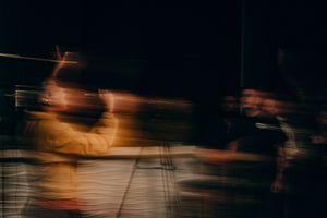 Long exposure motion blur photograph of subway train passing through dark tunnel with orange lights and reflections.
