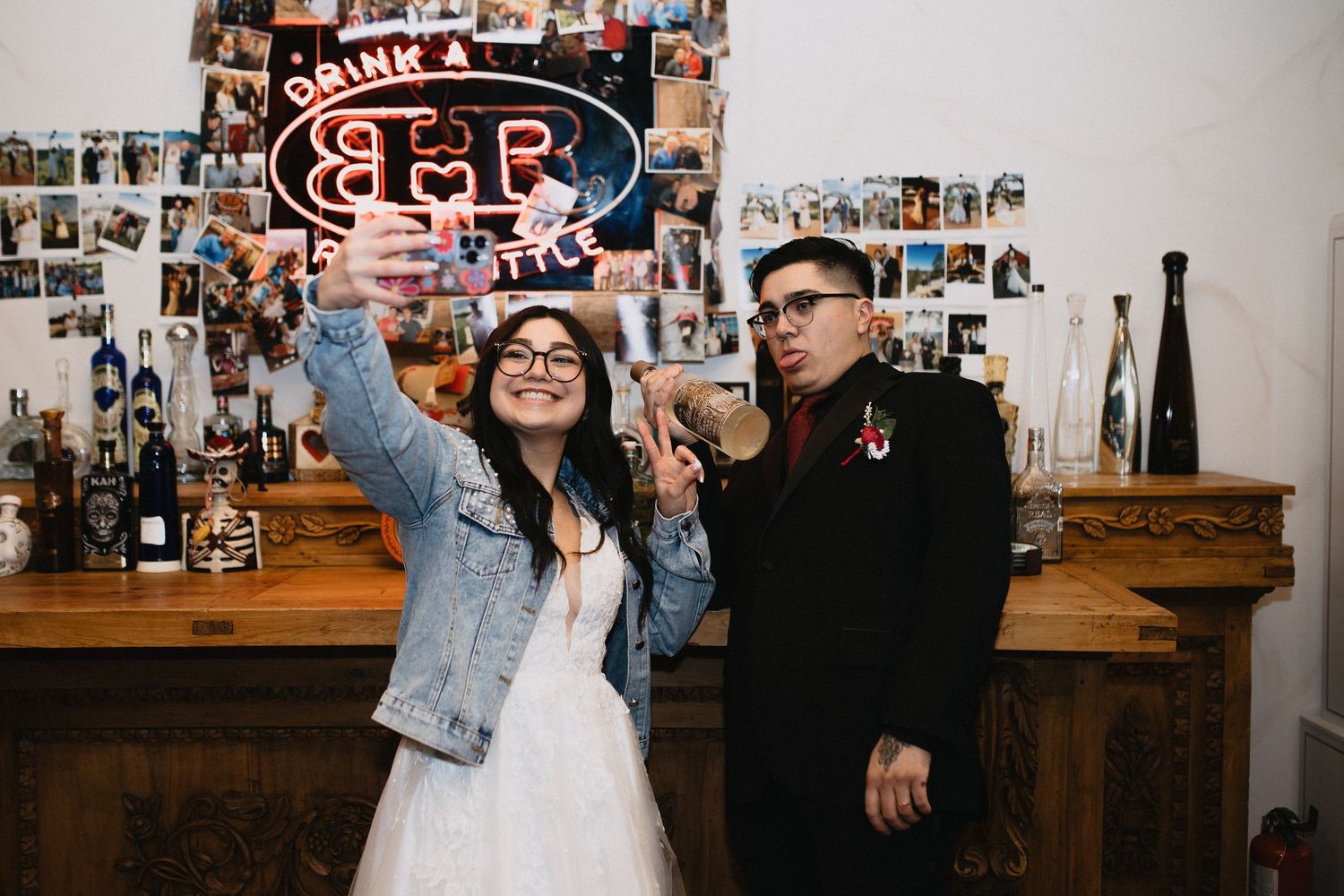 Bride and groom pose with a neon beer sign at a fun, eclectic wedding reception bar.cinematic wedding photographer new mexico