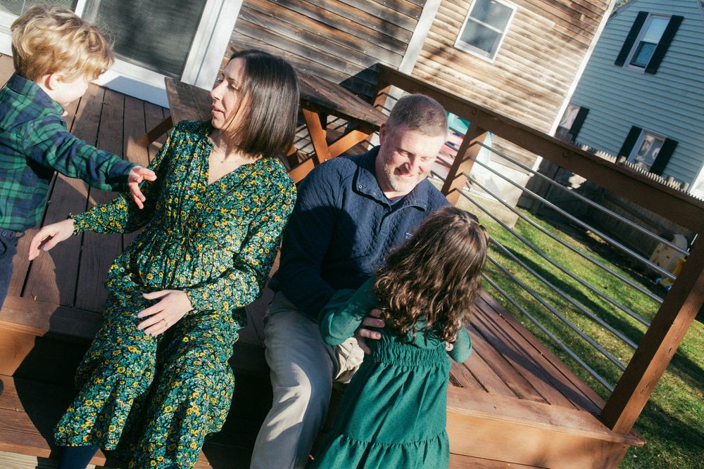 Family of four getting ready to pose for a photo, candid shot of the children going in for a hug in the autumn in Portland, Maine.